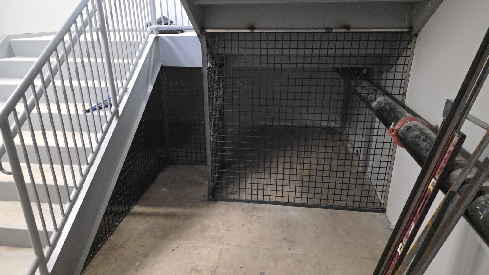 Commercial steel stair with welded safety cage and mesh panels