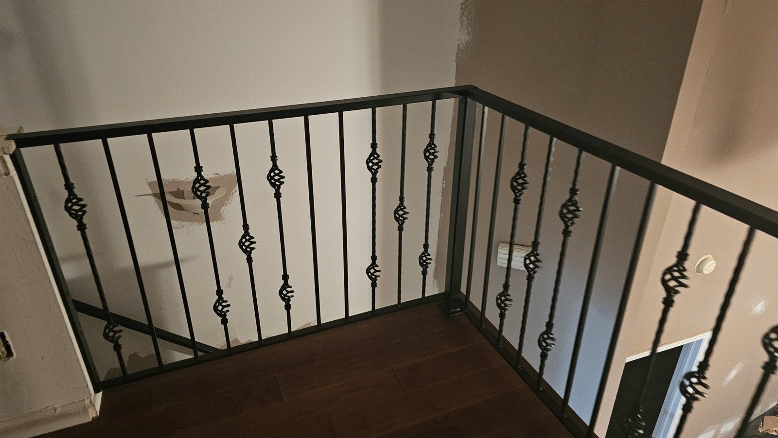 Decorative basket twist steel balusters on an indoor landing railing