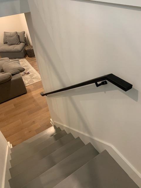 Minimal black wall mounted steel handrail on a modern staircase