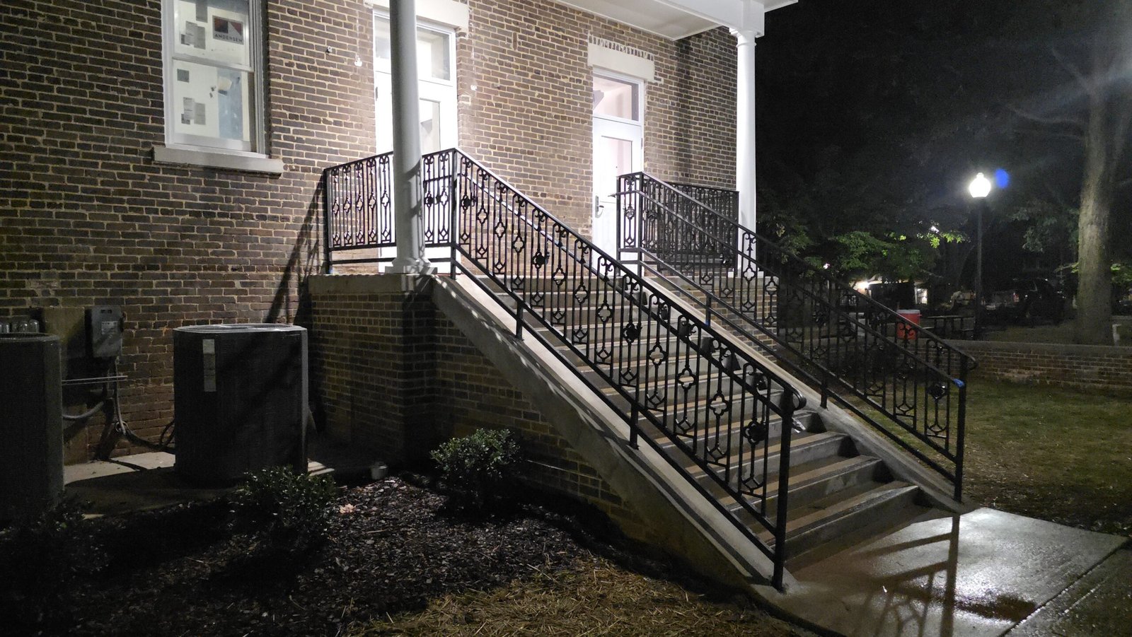 Custom ornamental exterior stair railing at night on a brick commercial building